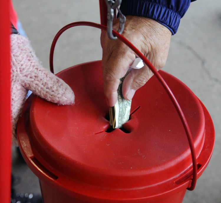 Tammy Sumabat holds a Salvation Army kettle still while a patron puts a donation into it last week at Sam’s Club in Augusta.