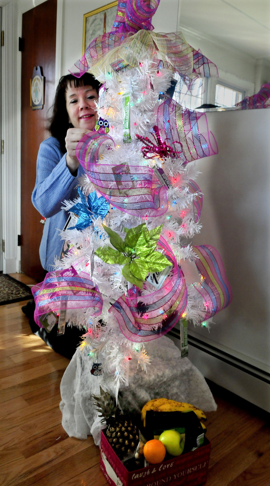 Morning Sentinel columnist Amy Calder arranges gift cards on Tuesday on the Christmas tree she won at the Sukeforth Family Festival of Trees last month. She nicknamed the 4-foot-tall tree “Little White.”