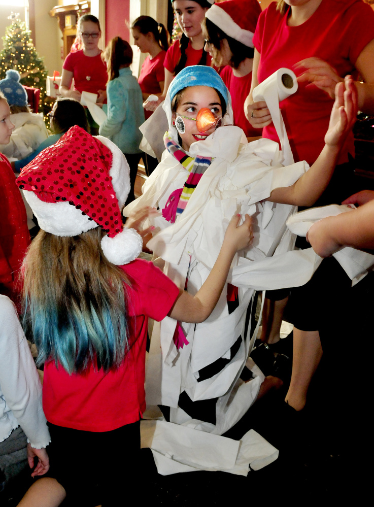 Chloe Dubois of Triple C Dance and Top Hat School of Dance gets wrapped in toilet paper as she becomes Frosty the Snowman with help from Caitlyn Cote, left, and others during an event of the Festival of Trees at Good-Will Hinckley on Sunday.
