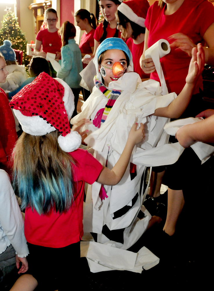 Chloe Dubois of Triple C Dance and Top Hat School of Dance gets wrapped in toilet paper as she becomes Frosty the Snowman with help from Caitlyn Cote, left, and others during an event of the Festival of Trees at Good-Will Hinckley on Sunday.