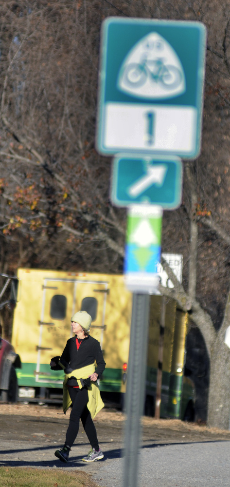 Pat Connors exits the Kennebec River Rail Trail Monday near her home in Hallowell. Signs marking the East Coast Greenway bike trail have gone up in Augusta and Hallowell recently, as the trail continues to try to expand its reach through all of Maine and down to Florida.