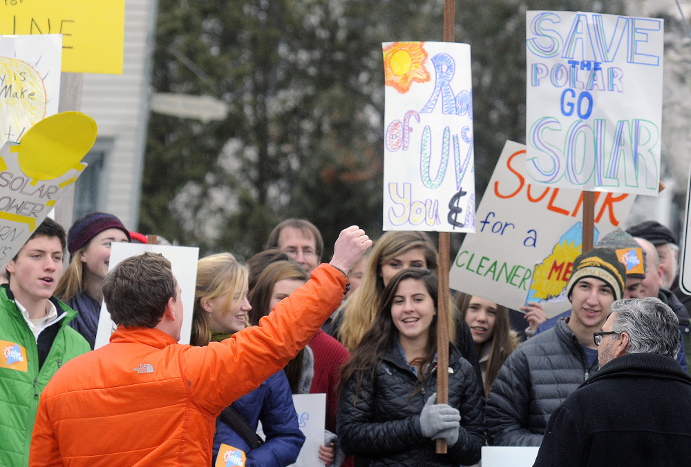 Natural Resources Council of Maine employee Todd Martin cheers Wednesday at a gathering of solar power supporters outside the Public Utilities Commission headquarters in Hallowell.