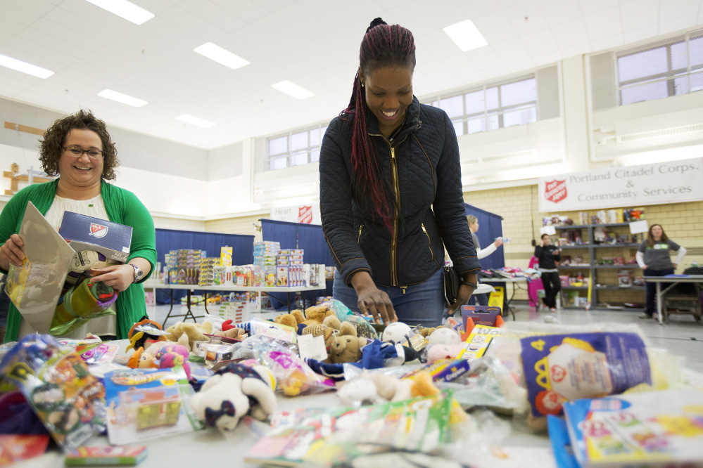 Viola Lupai looks through a table of stuffed animal toys Thursday at the Salvation Army’s annual toy distribution program in Portland, which is funded by kettle donations, while volunteer Jessica Nason helps carry Lupai’s toys.