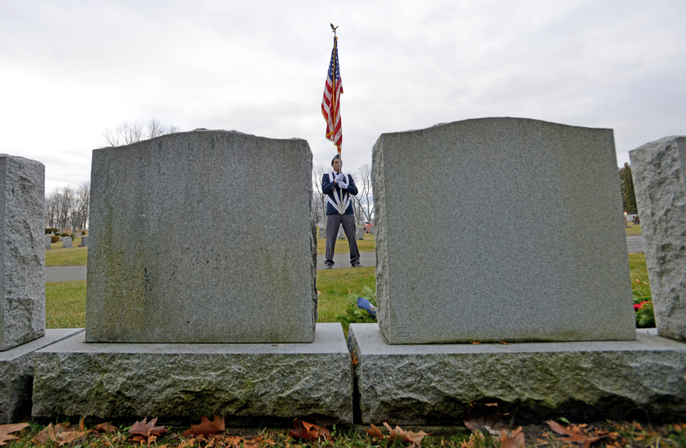 Bryant Bourgoin, a member of the men’s auxillary of Waterville VFW Post 1285, stands at attention with the American flag during a wreath-laying ceremony Saturday at St. Francis Cemetery on Grove Street in Waterville. The wreaths, from Wreaths Across America, are being placed on veterans’ graves across the nation.