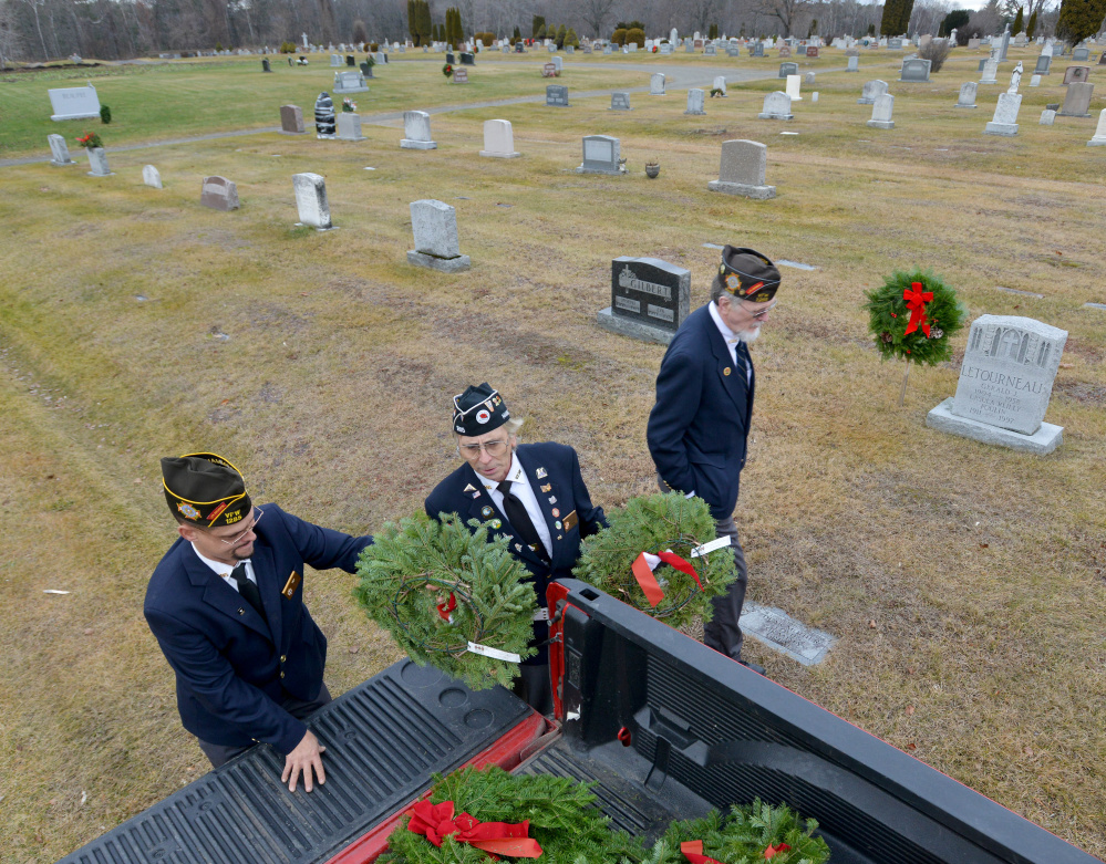 Waterville VFW Post 1285 Commander Daniel Parker, left, hands out wreaths Saturday to Paul Pontbriand, center, and Charles McGillicuddy, right, at St. Francis Cemetery on Grove Street in Waterville.