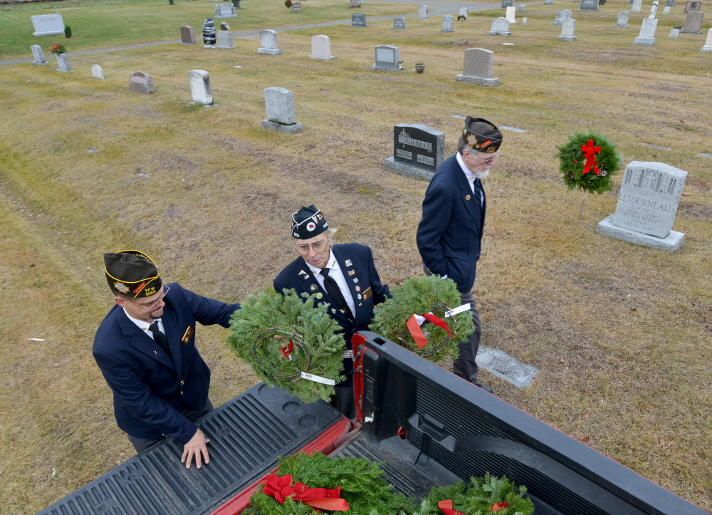 Waterville VFW Post 1285 Commander Daniel Parker, left, hands out wreaths on Saturday to Paul Pontbriand, center, and Charles McGillicuddy, right, at St. Francis Cemetery on Grove Street in Waterville.