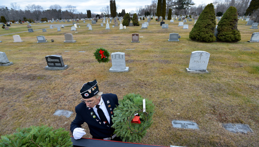 Paul Pontbriand, president of Waterville VFW Post 1285’s men’s auxiliary, grabs wreaths from a pickup truck to delivers them to veterans’ graves Saturday at St. Francis Cemetery on Grove Street in Waterville.