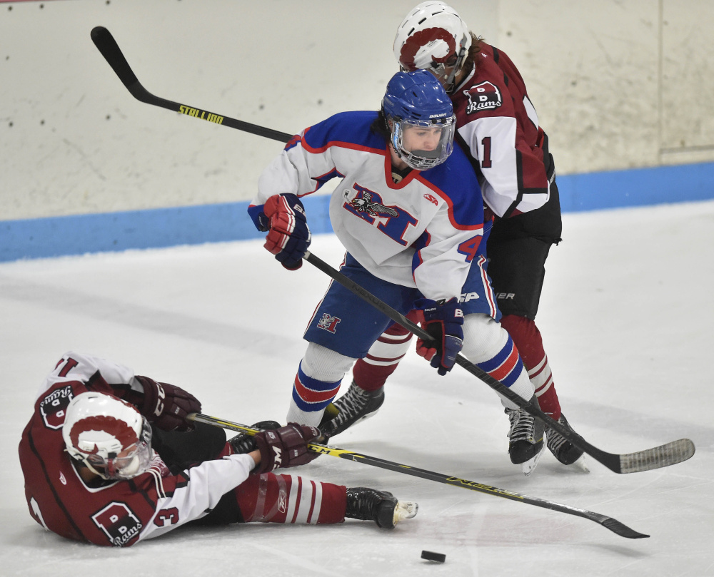 Messalonskee High School’s Sam Bell, center, battles for the puck with Bangor High School’s Cameron Burpee (13) left and Ben Lane (11), right, Saturday at Sukee Arena in Winslow.
