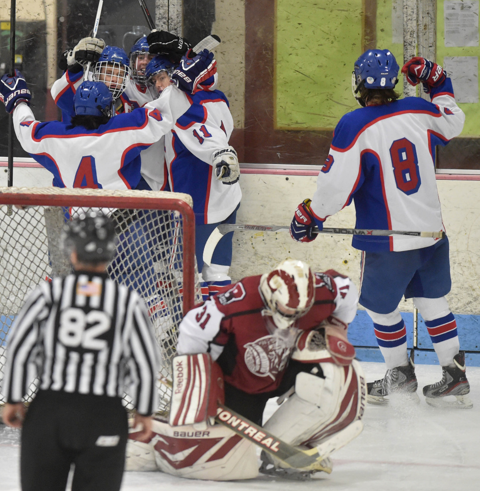 Messalonskee High School’s Jared Cunningham, center back, is swarmed by teammates as Bangor High School goalie Derek Fournier (31) takes a knee in the second period Saturday at Sukee Arena in Winslow.