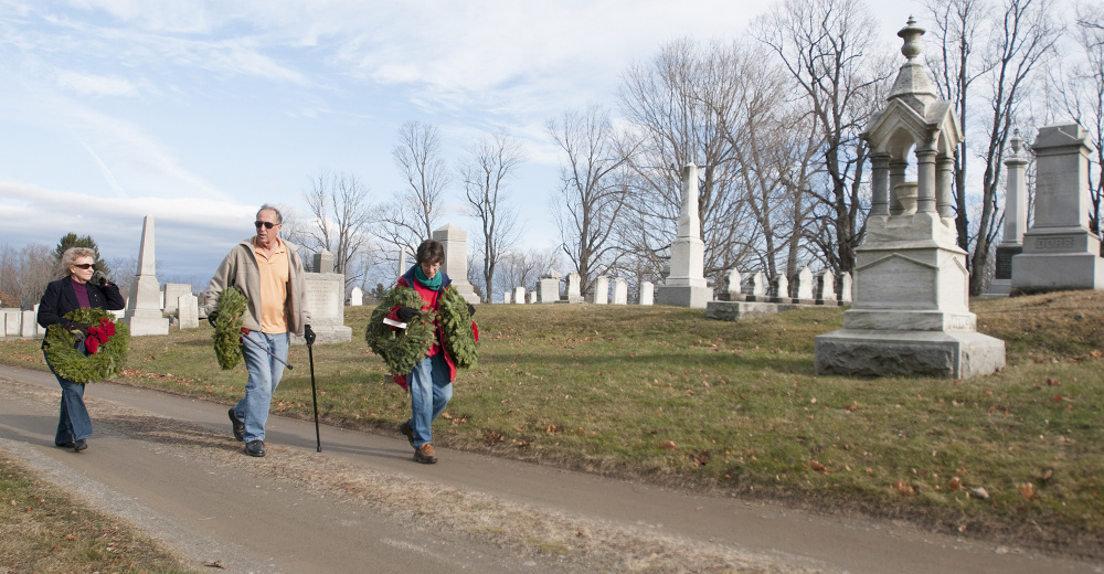 Rod and Lydia Tenney, left, and Annie Cough, all of Gardiner, look for veterans’ graves where they can lay wreaths Saturday in Oak Grove Cemetery in Gardiner. Organizer Steve Hanley of American Legion Post 4 in Gardiner said 525 veterans are buried in area cemeteries, but his group could raise only enough money to buy 230 wreaths for the graves.