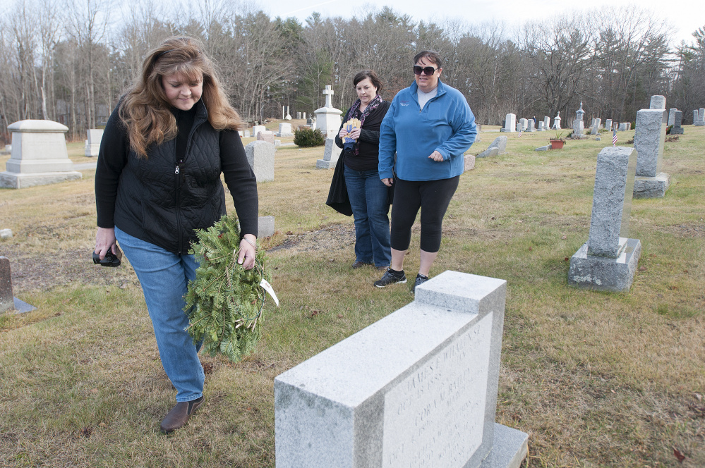 Lisa Gilliam, of Gardiner, lays a wreath Saturday on the grave of a veteran as Trisha Leathers, center, and Kathy Cutler watch in Oak Grove Cemetery in Gardiner. Organizer Steve Hanley of American Legion Post 4 in Gardiner said 525 veterans are buried in area cemeteries, but his group could raise only enough money to buy 230 wreaths for the graves.