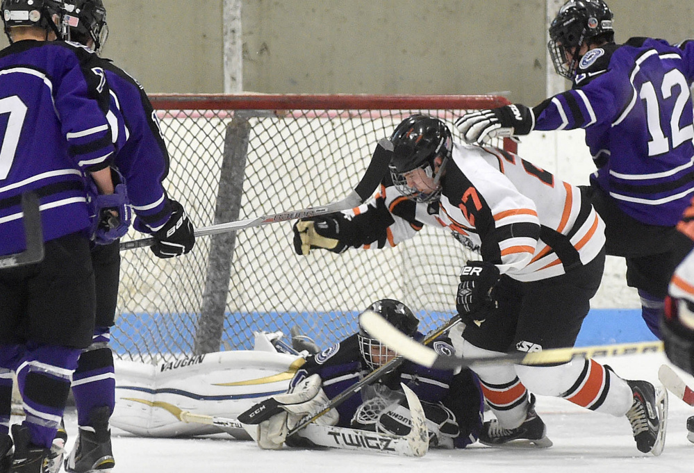 Waterville Senior High School goalie Nathan Pinette (30) falls on the puck as Winslow High School’s Nick West (27) tries to grab the rebound and Waterville’s Zachary Smith (12) tries to defend Saturday at Sukee Arena in Winslow.
