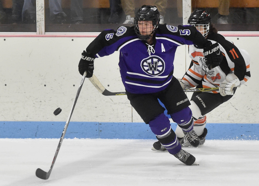 Waterville Senior High School’s Andrew Rodrigue (5) skates away with the puck as Winslow High School’s Logan Denis (11) pursues Saturday at Sukee Arena in Winslow.