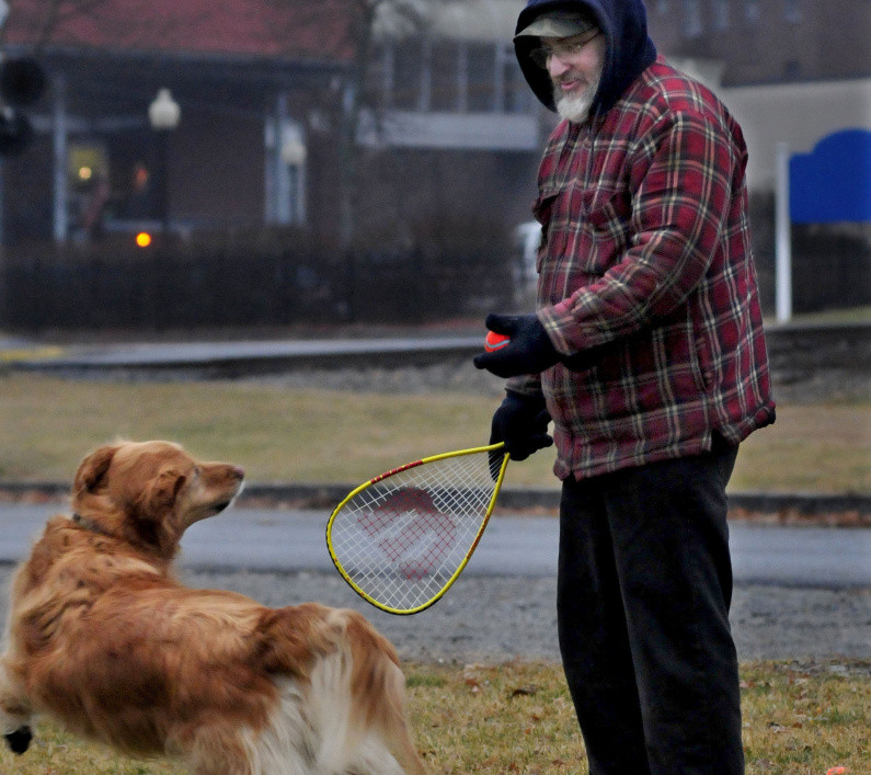 Ray Cole gets ready to hit a ball with a racquet ball racket for his dog Bubba at Head of Falls in Waterville on Monday. “This is a good stress reliever for me,” Cole said as the two enjoyed the mild weather, which is expected to continue until the end of the month.