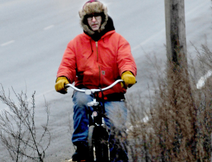 Tim Jurdak rides his bike in Waterville during a misty day on Monday. Asked about the weather Jurdak said, “I prefer snow over the freezing rain that is supposed to come later tonight.” The mild weather is expected to continue until at least the end of the month.