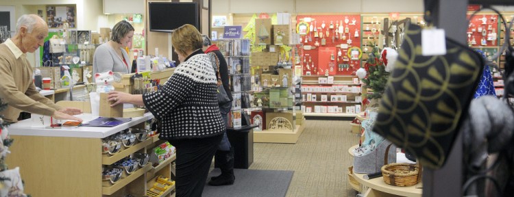Customers purchase gifts Monday at Stacy’s Hallmark in Augusta. The Water Street business is closing at the end of the year and the building is being sold.