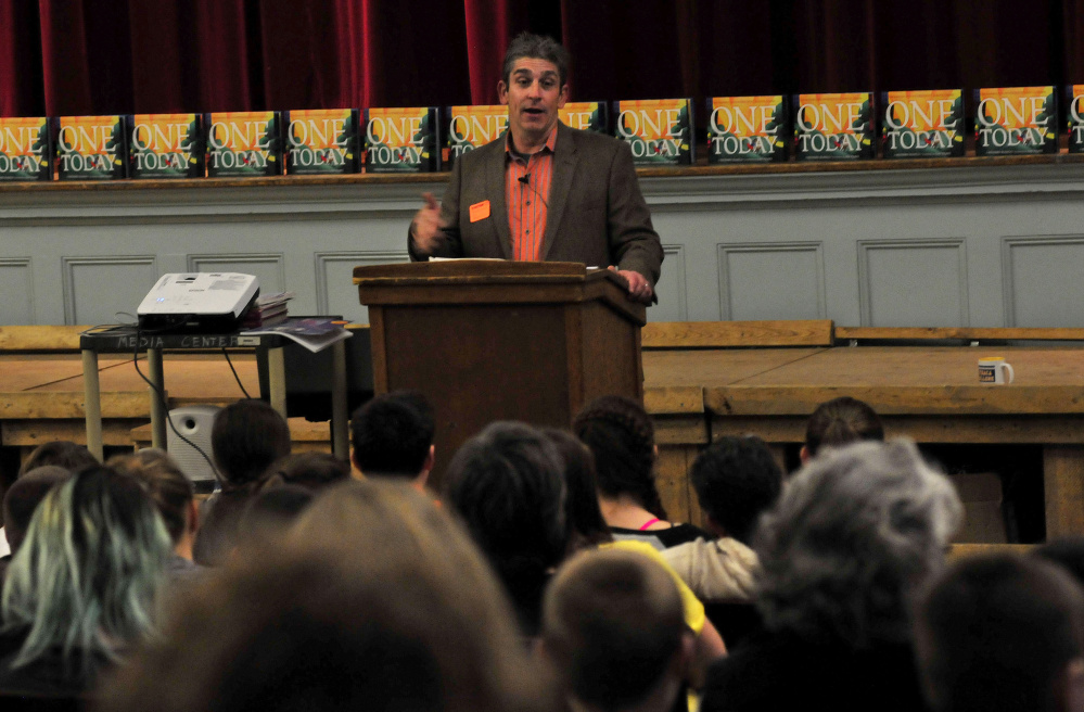 Poet Richard Blanco reads one of his poems to students at Winslow Junior High School on Tuesday.  His book “One Today” is behind him. Blanco was scheduled to read later Tuesda at Waterville’s Opera House.