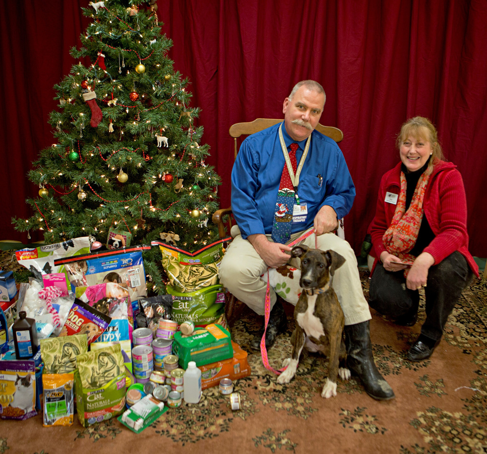 Howard Mette, a department director at Inland Hospital, poses in front of the gifts donated by hospital workers to the Humane Society Waterville Area shelter. With Mette are Paisley, a shelter resident, and shelter Director, Lisa Smith.