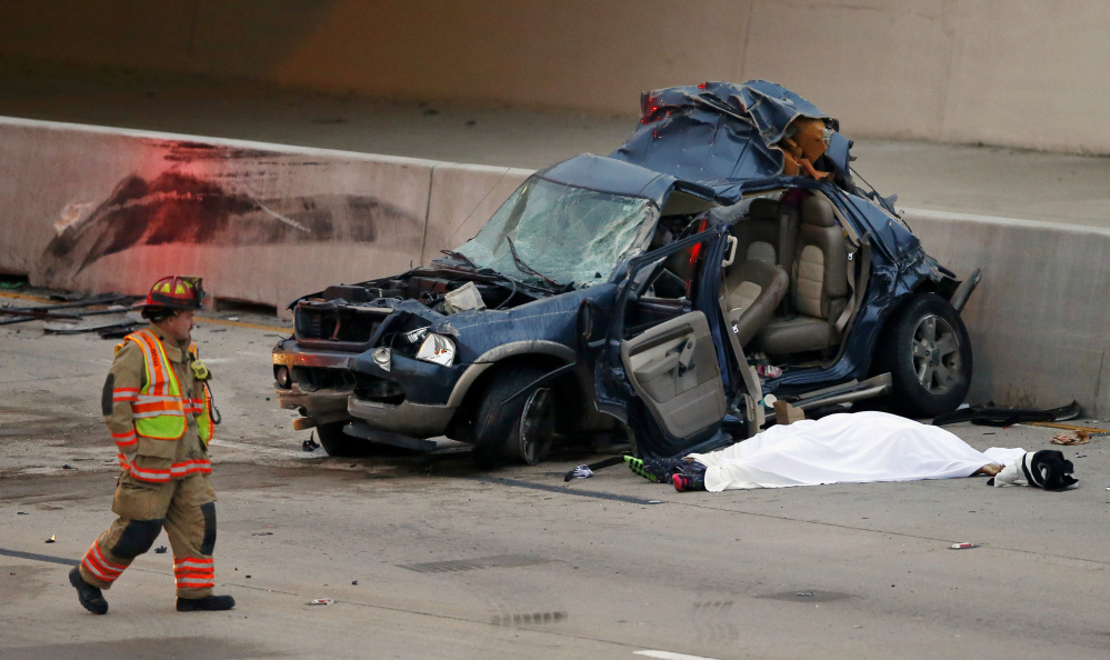 An Arlington firefighter inspects an SUV that was hit by a Greyhound bus in the fast lane on westbound Interstate 30 near Collins St. in Arlington, Texas, killing one, under sheet, in the vehicle early Sunday.