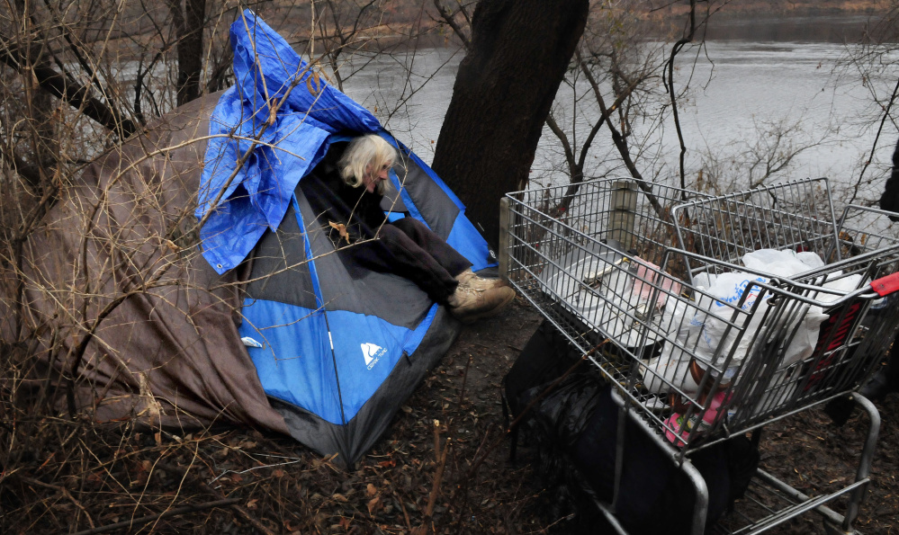 Homeless man Vaughan Orchard climbs out of his tent where he lives along the Kennebec River in Waterville on Tuesday.