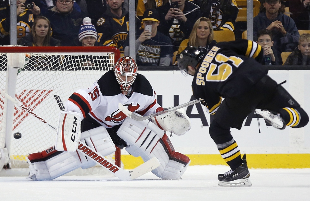 Boston’s Ryan Spooner (51) scores on New Jersey goalie Cory Schneider in a shootout Sunday in Boston. The Bruins won 2-1.