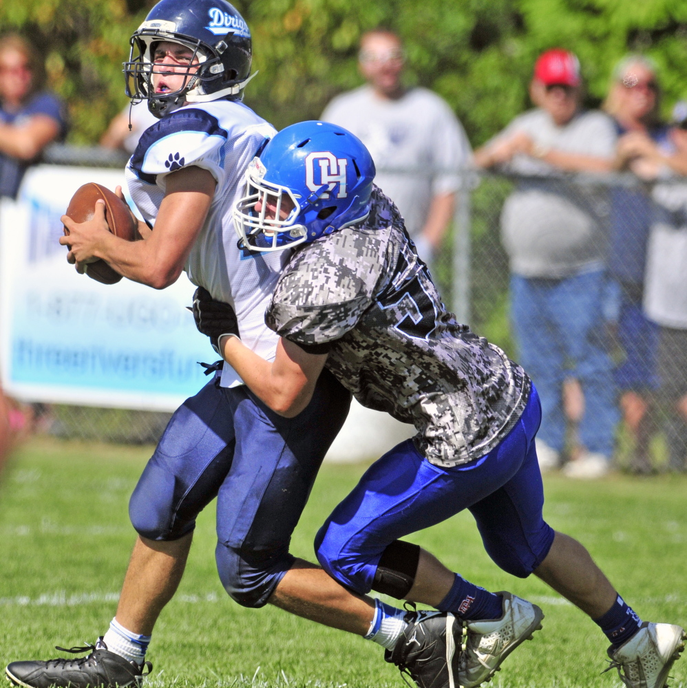 In this Sept. 12 photo, Dirigo quarterback Riley Robinson, left, gets sacked by Oak Hill defensive lineman Connor Elwell during third quarter of a game in Wales.