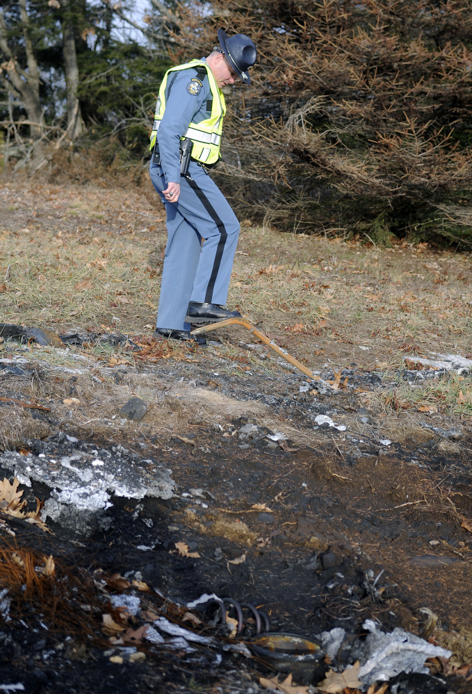 Trooper Greg Stevens inspects burned metal last week from a tractor-trailer that erupted into flames after striking his police cruiser July 30 on Interstate 295 in Richmond.