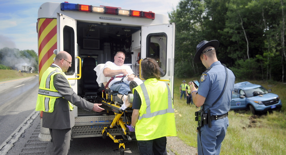 Maine State Police and medics load Trooper Greg Stevens into an ambulance July 30 after his cruiser was struck by a tractor-trailer in the northbound lanes of Interstate 295 in Richmond.