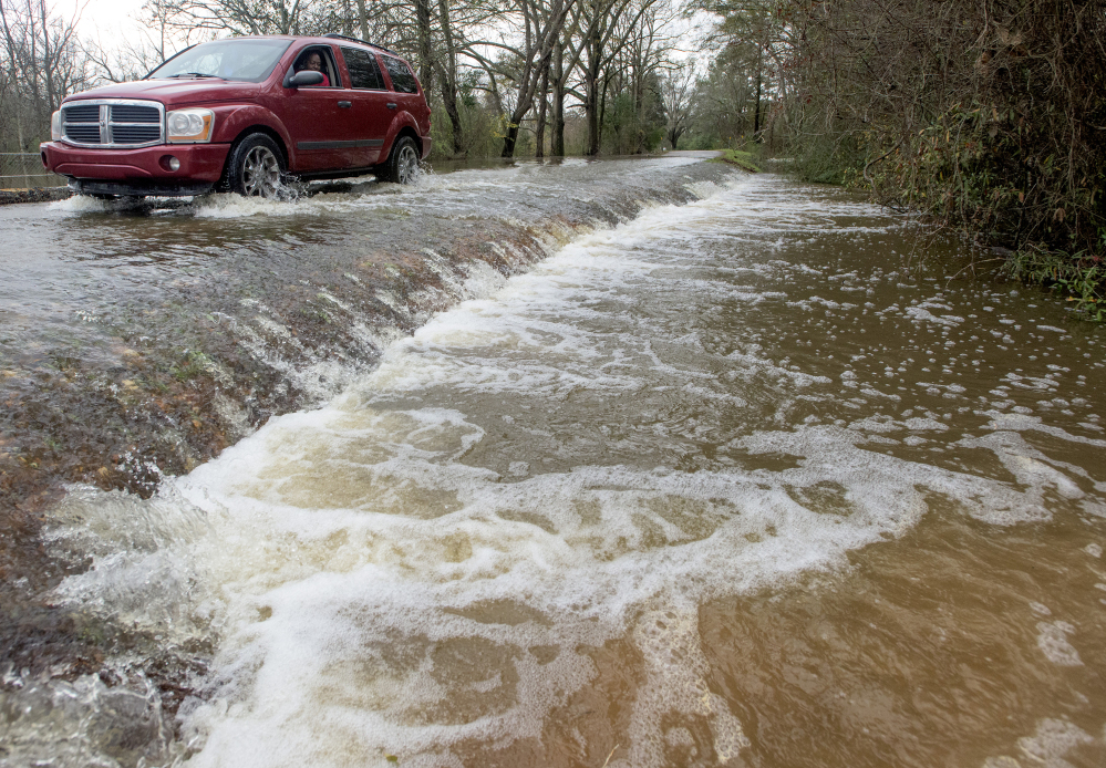 A vehicle drives along a flooded road in west Montgomery, Ala., on Christmas morning Friday. The line of springlike storms continued marching east Thursday, dumping torrential rain that flooded roads in Alabama and caused a mudslide in the mountains of Georgia.