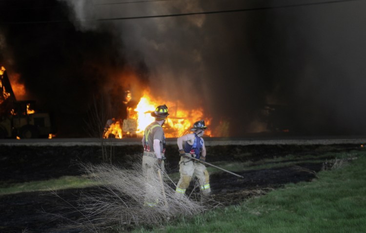 Shrouded in smoke, firefighters react to an explosion May 5 while attempting to extinguish a brush fire that extended from a blaze that destroyed AD Electric on South Monmouth Road in Monmouth.