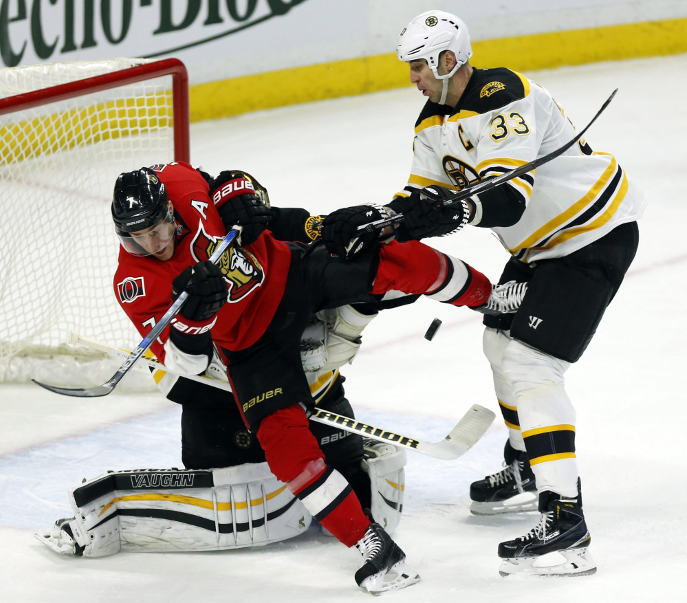 Ottawa Senators’ Kyle Turris (7) is checked by Boston Bruins’ Zdeno Chara (33) in front of the Boston net during first period action in Ottawa on Sunday.
