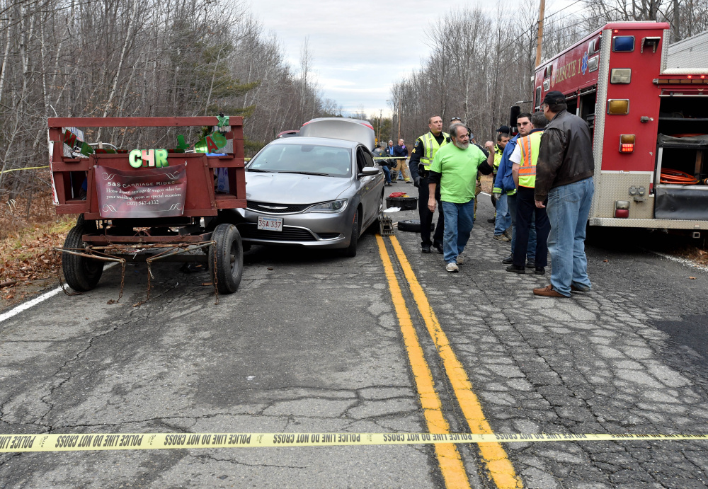 Rescue workers from Waterville fire department and Delta Ambulance tend to multiple victims after a horse-drawn wagon was hit by a car Christmas Day. One of those injured in the crash, Kathy Marciarille, of Rome, died Sunday night.