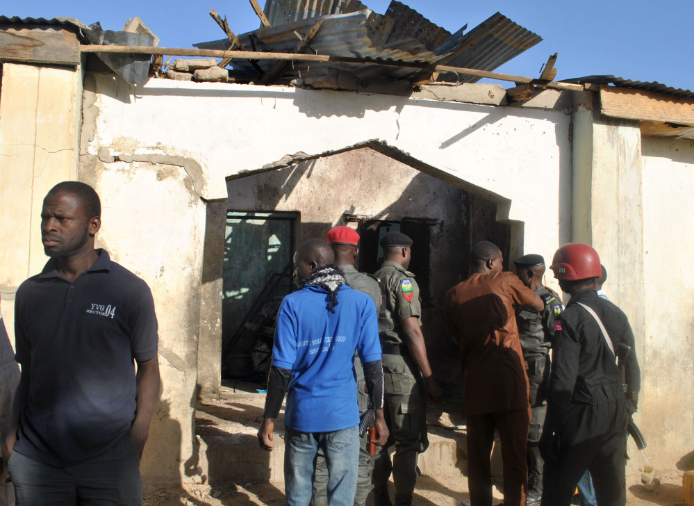 People gather at a damaged building following an attack by Boko Haram in Maiduguri, Nigeria Monday.