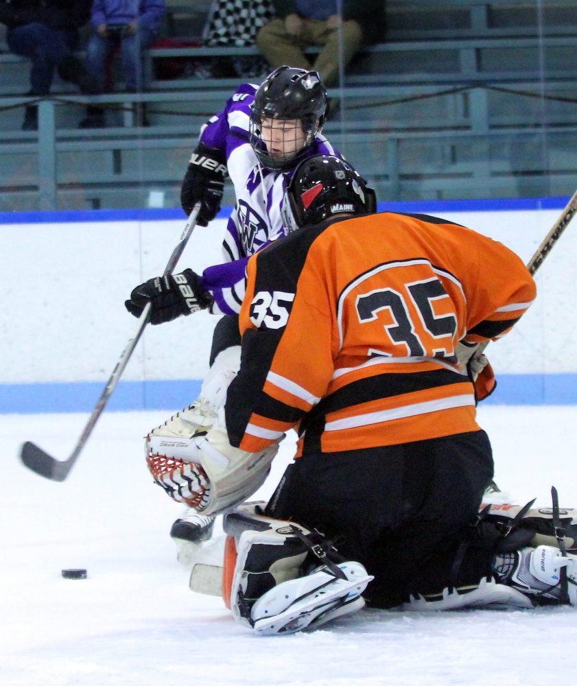 Waterville Senior High School’s Andrew Roderigue tries to put a rebound past Winslow High School goalie Andrew Beals during first-period action at Colby College in Waterville on Monday. The teams played to a 4-4 overtime tie.