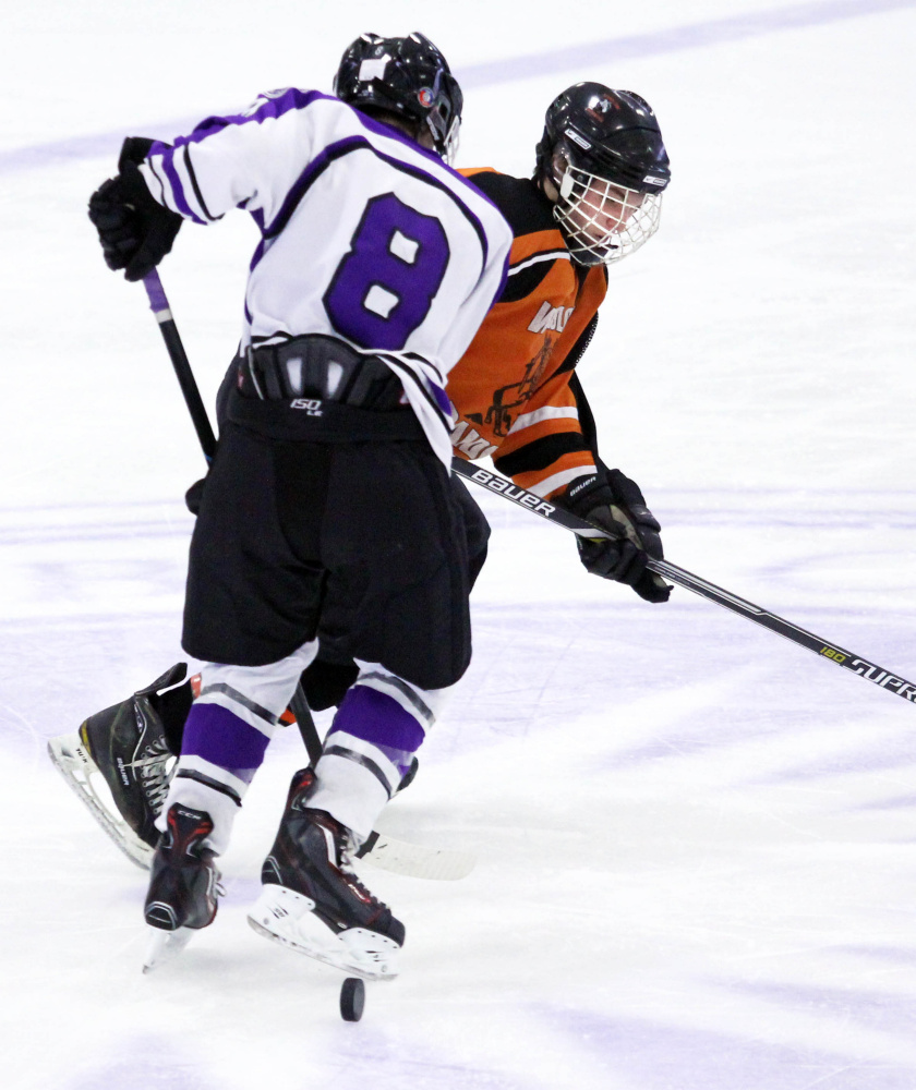 Winlsow High School’s Jimmy Fowler get checked off the puck by Waterville Senior High School’s Justin Wentworth during second-period action at Colby College in Waterville on Monday. The teams played to a 4-4 overtime tie.