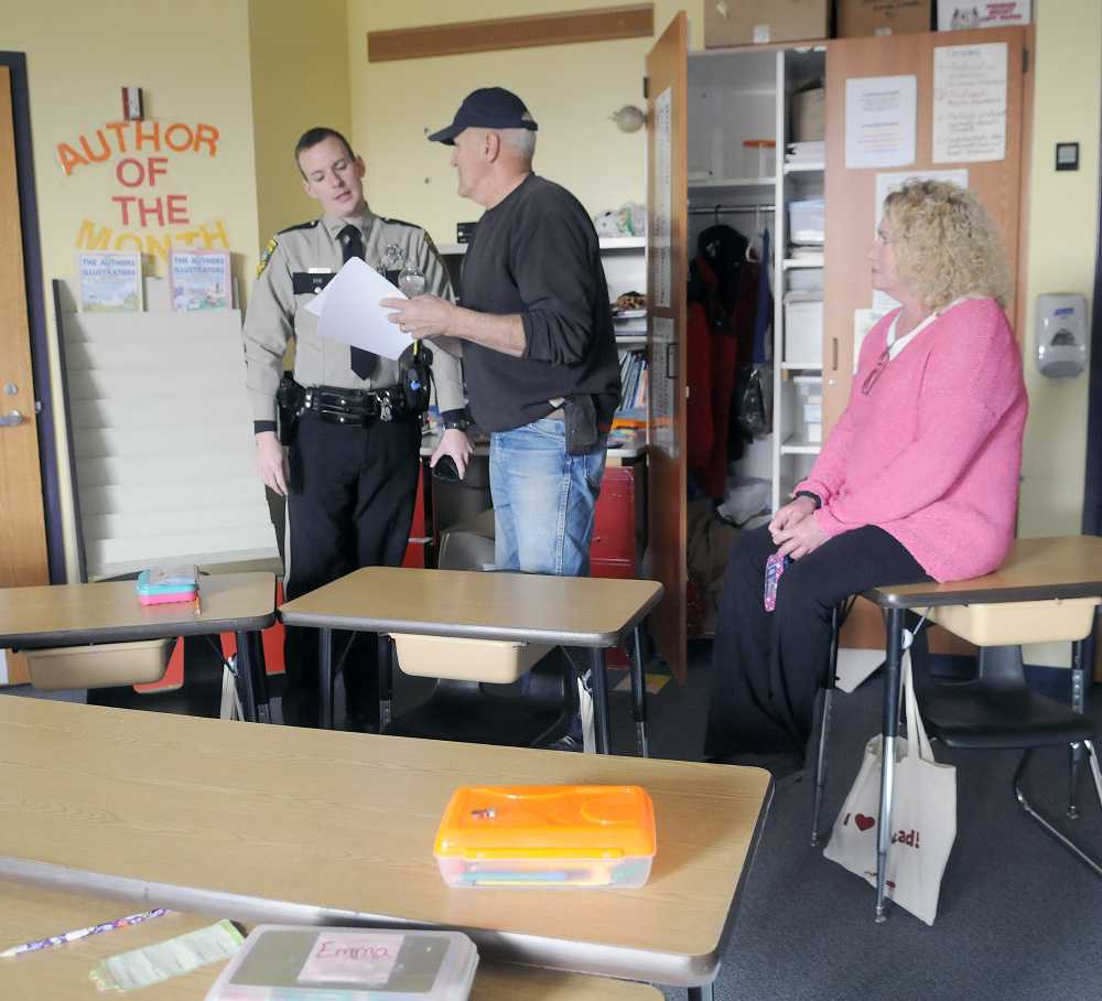 Deputy Aaron Moody, head custodian Stan Labbe and principal Christine Lajoie-Cameron on Monday discuss items, including a flat screen television, taken from a classroom at the Carrie Ricker School in Litchfield.