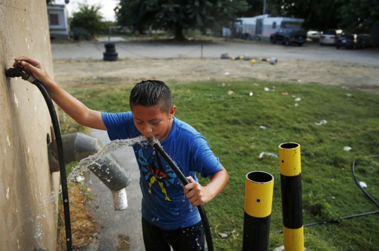 Carlos Velasquez, 9, drinks well water from a hose at a trailer park near Fresno, Calif.