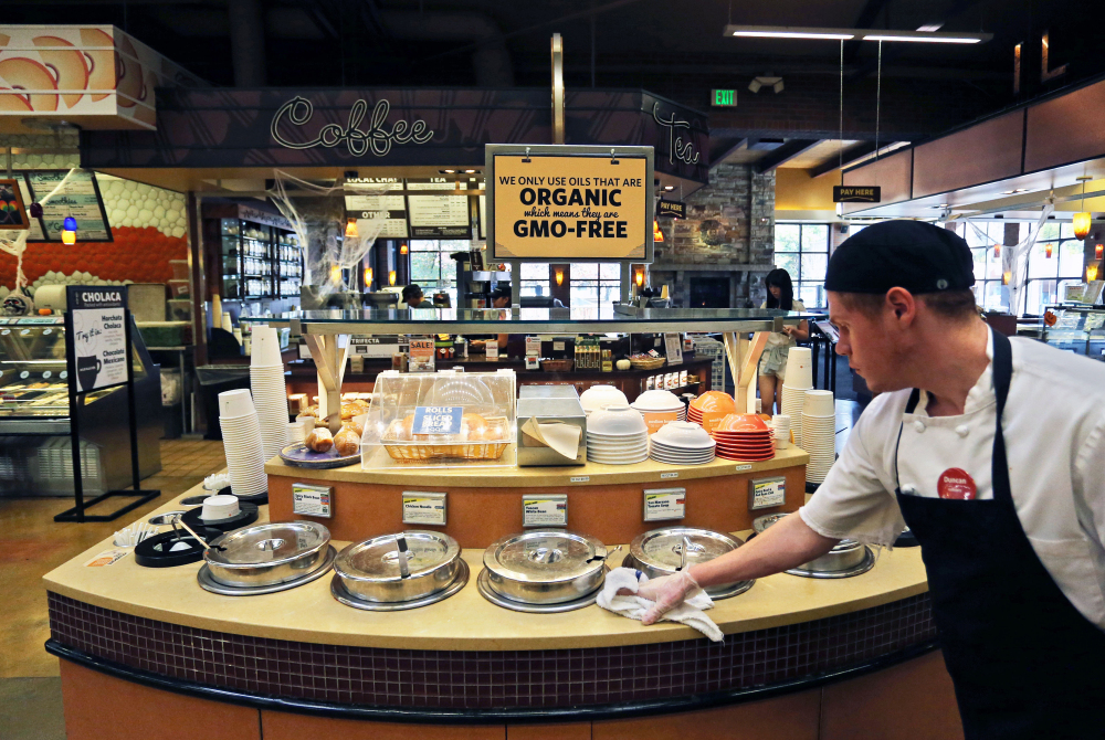 A grocery store employee wipes down a soup bar with a display informing customers of organic, GMO-free oils, in Boulder, Colo.
