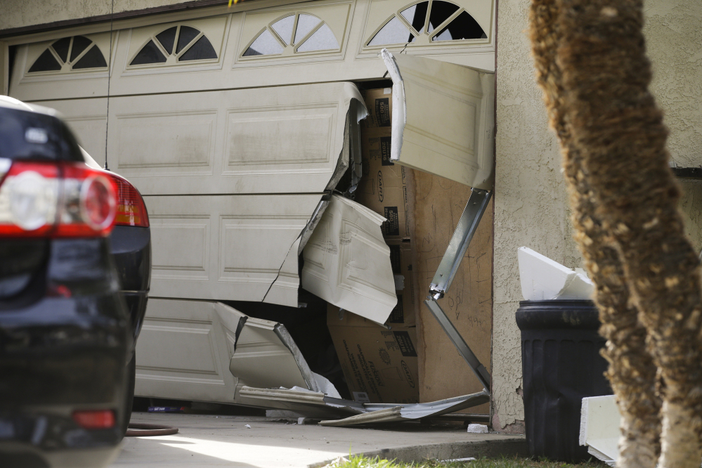 A garage door of Enrique Marquez’s home is broken Dec. 9 after an FBI raid in Riverside, Calif. Marquez, a former security guard who bought the assault rifles used by his friend in the San Bernardino massacre, was charged Thursday.