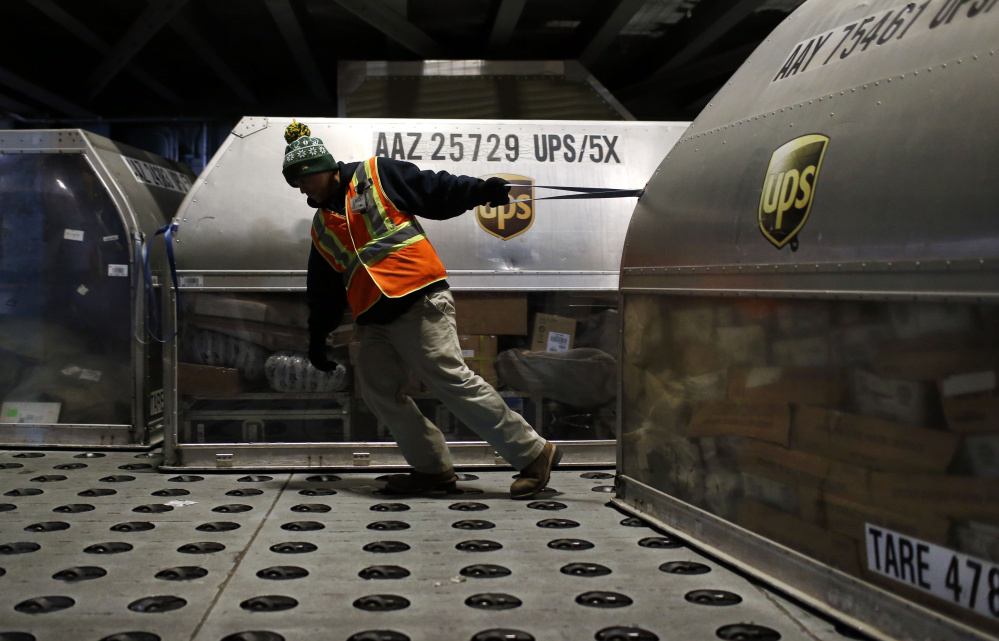 A UPS worker pulls a container full of packages across a floor embedded with casters at Worldport in Louisville, Ky. UPS will deliver 36 million packages Tuesday.