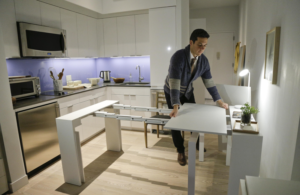 Stage 3 Properties co-founder Christopher Bledsoe demonstrates a desk that expands into a dining table inside one of the mini-apartments at Carmel Place in New York.