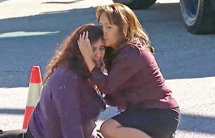Two women comfort each other near the scene of the mass shooting outside a social services center in San Bernardino, Calif. KNBC via AP