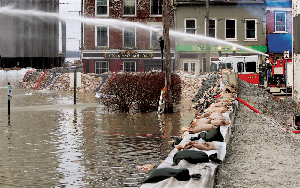 Firemen spray water towards water seepage under the city’s makeshift flood levee in downtown Alton, Ill., Wednesday.