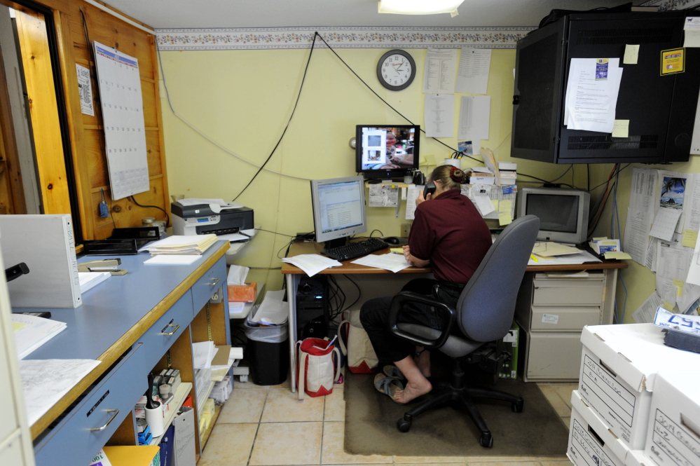 Kathy Gray, dispatcher for the Oakland Police Department, works at her desk in July. The station, in a cramped farmhouse, will be replaced soon by a new building. The town might consider bids on the work next week.
