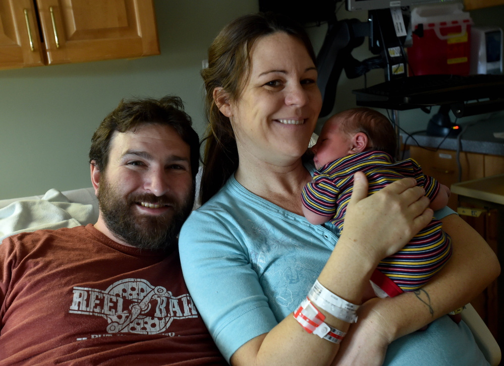 Levi Daku, left, and Meghan Bitterauf, right, cuddle with their new son, Isiah, on Saturday. Isiah was the first baby born in the region in the New Year and likely the first in Maine.