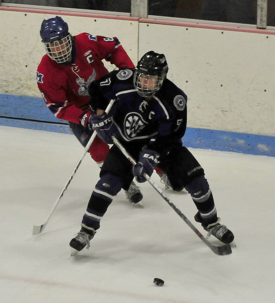 Messalonskee defenseman Dylan Burton, back, looks to contain Waterville forward Nick Denis during a Class B North game Wednesday night at Sukee Arena in Winslow.