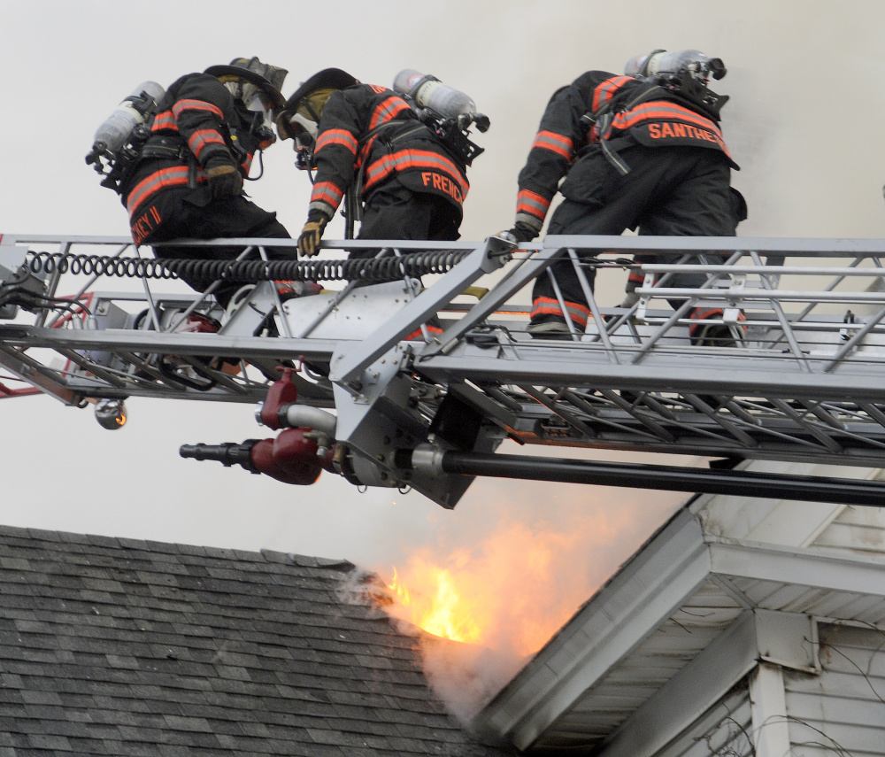 Gardiner firefighters pull a colleague to safety Wednesday after he broke through the roof 37 Riverview Drive in Gardiner.