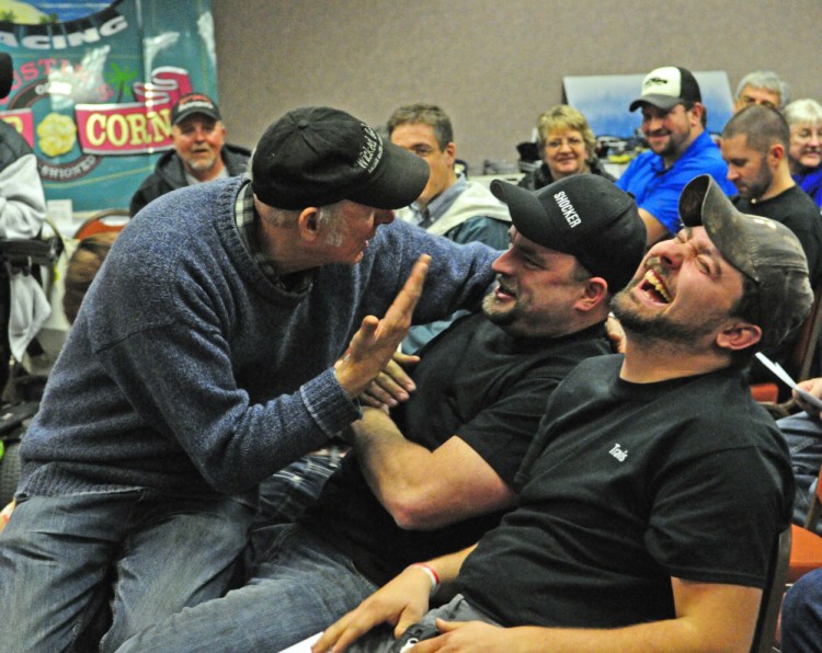 Rosey Gerry, left, sits in Zach Audet’s lap while cajoling him to bid higher during an auction Saturday at the Augusta Civic Center. Travis Pouliot laughs during the fundraiser for the Maine Vintage Race Car Association.