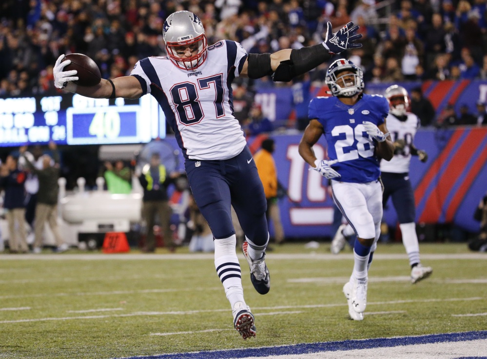 New England’s Rob Gronkowski scores a touchdown in front of New York Giants’ Jayron Hosley (28) during the second half earlier this season in East Rutherford, N.J. Gronkowski and the Patriots will host the Kansas City Chiefs in an AFC divisional round playoff game Saturday.