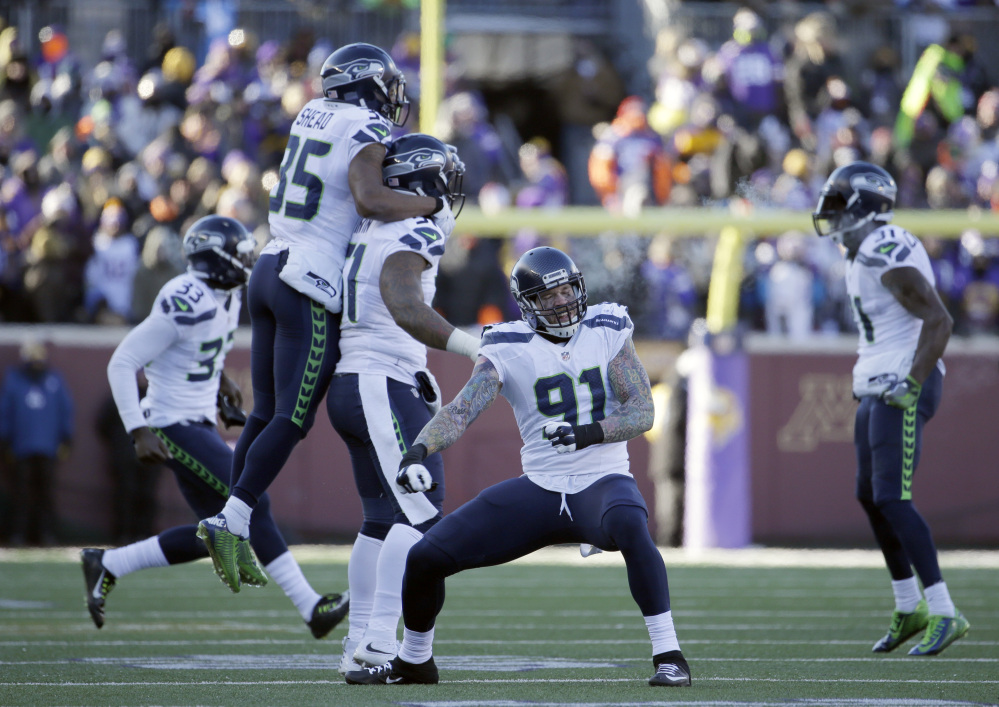 Seattle Seahawks defensive end Cassius Marsh (91) and defensive players celebrate a play against the Minnesota Vikings during an NFL wild-card game Sunday in Minneapolis.